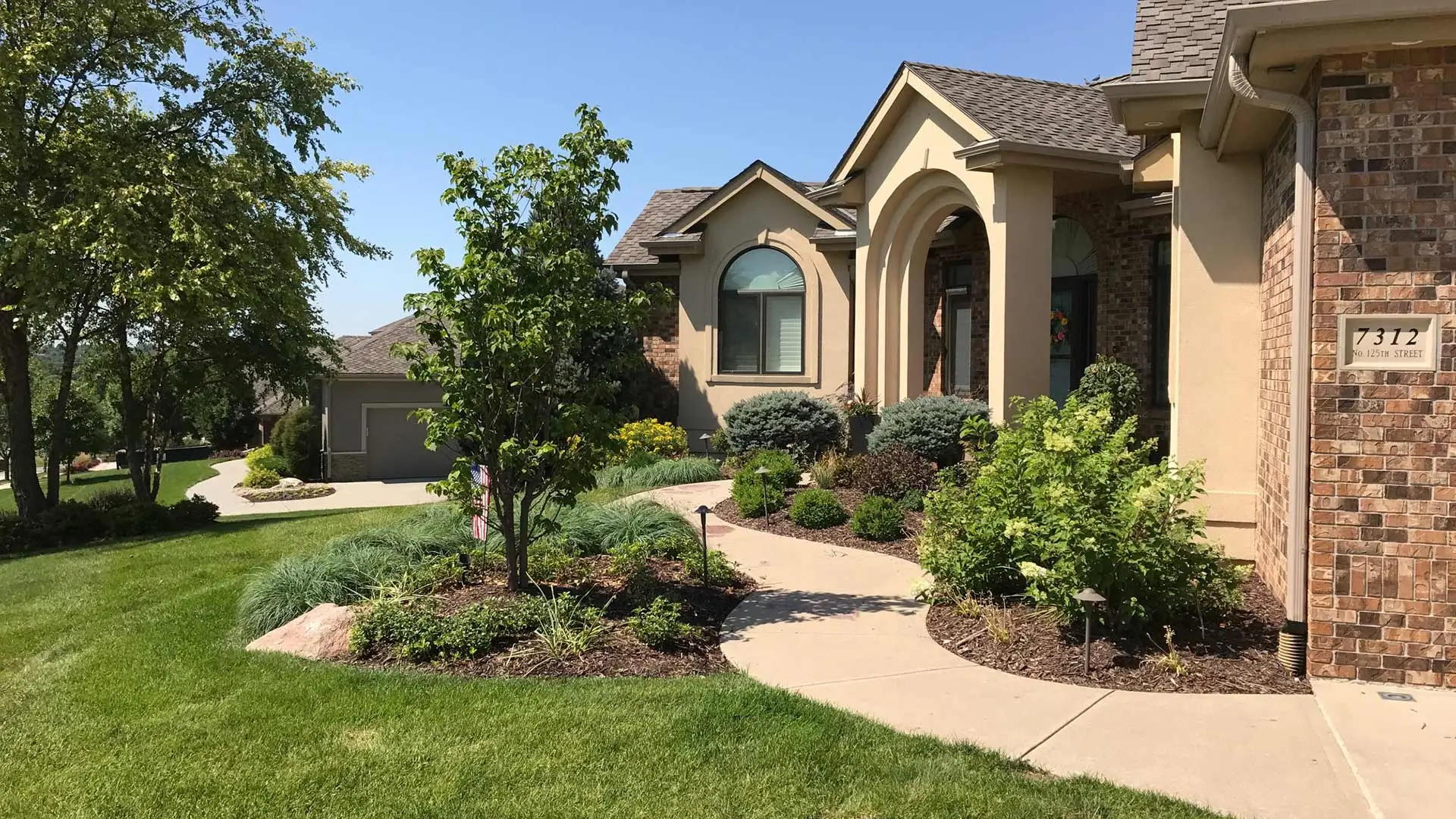 A home in Omaha, NE with fresh landscape beds and trees. 
